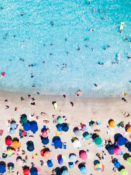 Photo of View from above, aerial view of an emerald and transparent Mediterranean sea with a white beach full of beach umbrellas and tourists who relax and swim. Costa Smeralda, Sardinia, Italy.