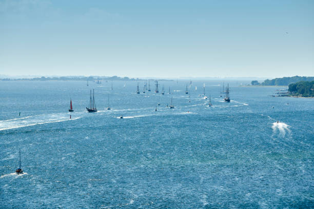 Sailboats arriving. View from high viewpoint, Summer and blue water and clear sky. Going against the wind with sails down and entering by motor engine.