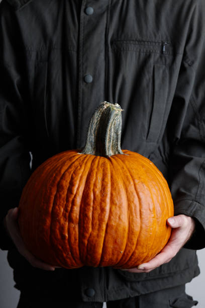istock Man holding large orange pumpkin in hands, close up view 1010292262