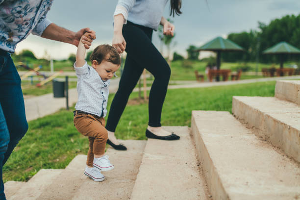 baby walking with help of its parents - first steps - shoe women adult baby imagens e fotografias de stock