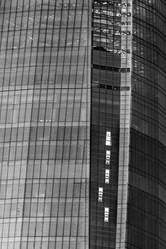 A textured pattern along the building construction of the skyscraper, perfect rectangles going up with a colorful contrast because of the twilight time