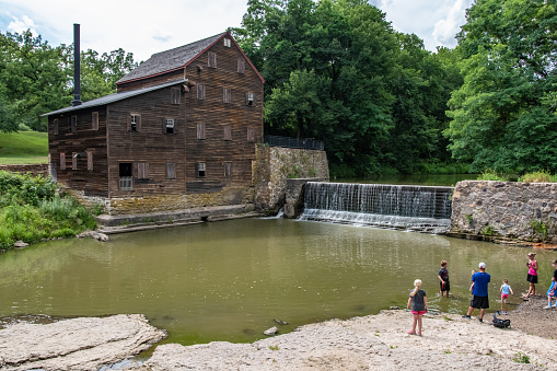 Muscatine County, Iowa/USA- July 18, 2018: A family looks across the water to the historic Pine Creek Gristmill build in 1848.