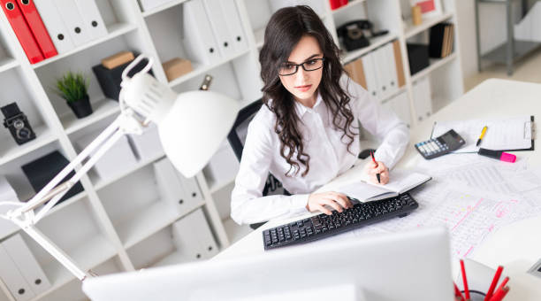 istock A young girl is working at the computer with a notepad and pen. 1010326896