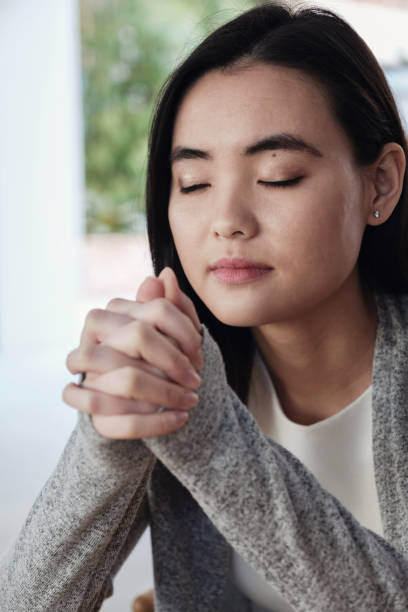 istock Young Asian woman praying with eyes closed 1010329480