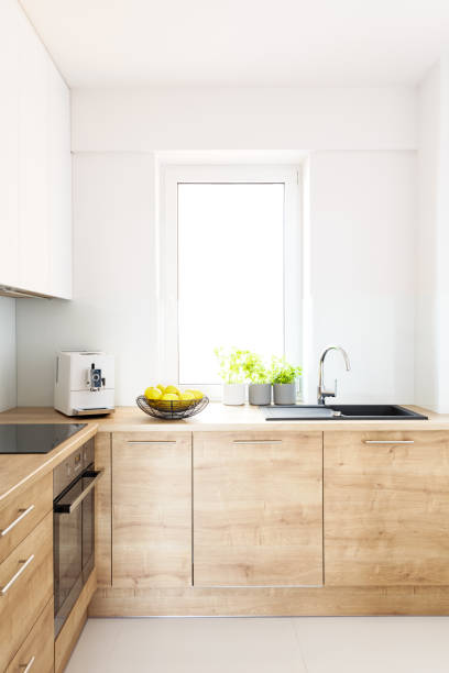istock Wooden cabinets in bright minimal white kitchen interior with window. Real photo 1010338938