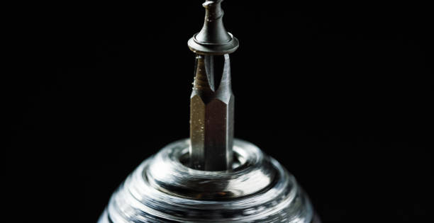 istock #2 Phillips Screwdriver Bit with a Carbon Steel Black Screw Head in a Power Drill Chuck Against a Black Background 1010375476