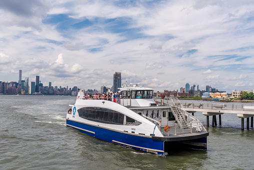 Brooklyn, New York, USA - July 8, 2017:  East River Ferry docking. Manhattan Midtown on background. New York, USA.
