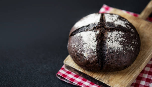 istock Fresh bread on black chalkboard background. Top view with copy space. Rye Bread on cutting board closeup
