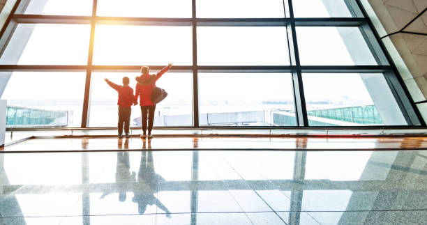 istock Mother and son looking through the window at airport 1010408348