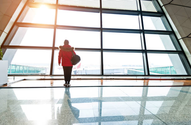 istock Woman looking through the window at  airport 1010408364