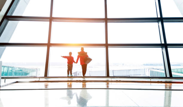 istock Mother and son looking through the window at airport 1010408486
