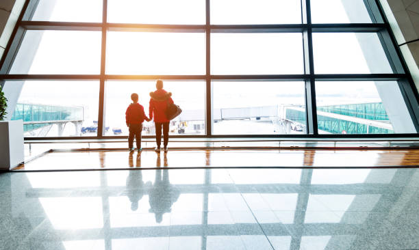 istock Mother and son looking through the window at airport 1010408492