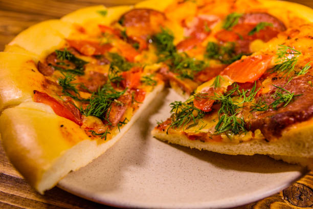 istock Ceramic plate with sliced homemade pizza on a wooden table 1010408624