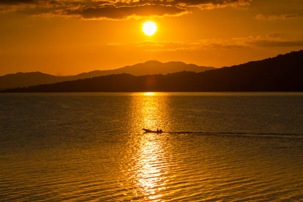 istock A long boat is crossing water in dam reflecting sunset 1010415766
