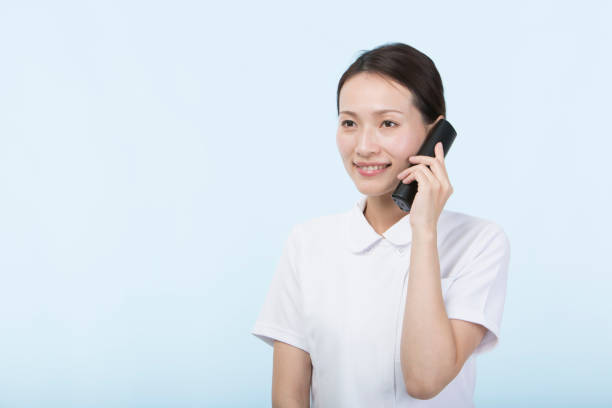 istock Woman wearing white uniform smiling holding a phone receiver 1010425560