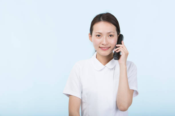 istock Woman wearing white uniform smiling holding a phone receiver 1010425582