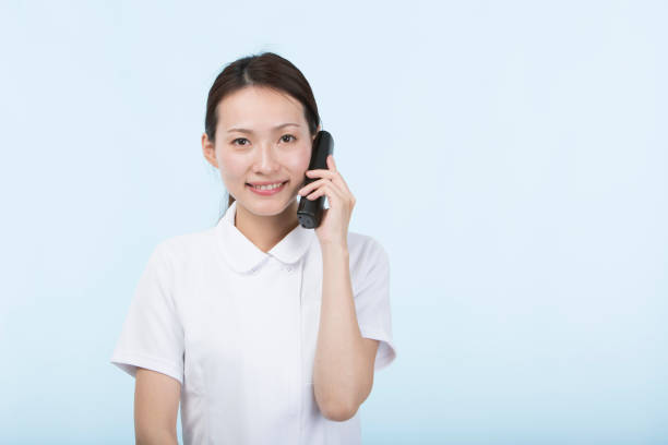 istock Woman wearing white uniform smiling holding a phone receiver 1010425608
