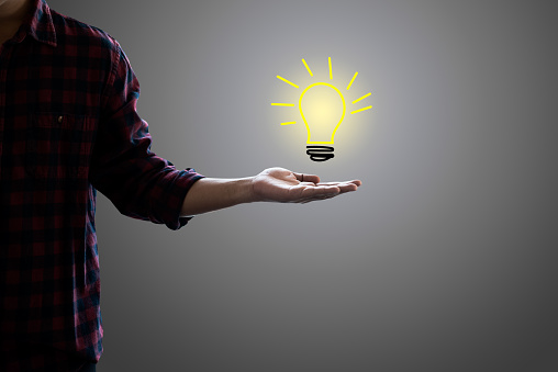 Drawing light bulb in hand businessman on gray background. concept for idea, innovation and inspiration