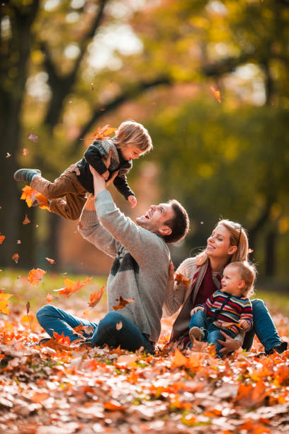 Young playful family having fun in autumn day at the park. Happy parents having fun with their small children in autumn day. young family photos stock pictures, royalty-free photos & images