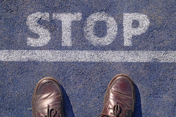 istock man in shoes standing before stop sign painted on asphalt, top view 1010461244