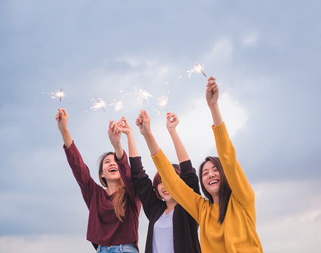 Happy group of asian girl friends enjoy and play sparkler at roof top party at evening sunset,Holiday celebration festive,teeage lifestyle,freedom and fun