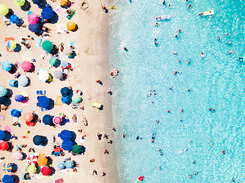 View from above, aerial view of an emerald and transparent Mediterranean sea with a white beach full of beach umbrellas and tourists who relax and swim. Sardinia, Sardinia, Italy.