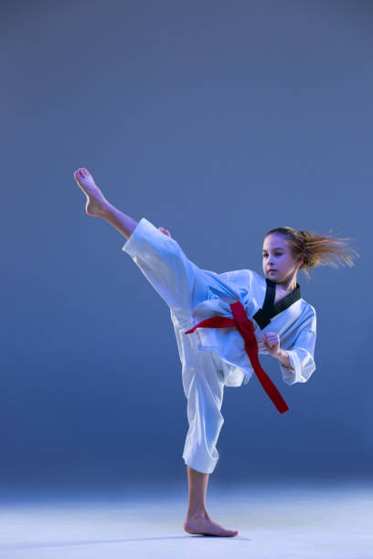 istock Young girl training karate on blue background 1010482776