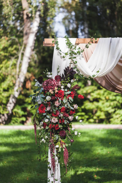 istock Wedding ceremony in rustic style decorated with different red flowers, white textile and chairs in forest 1010487906