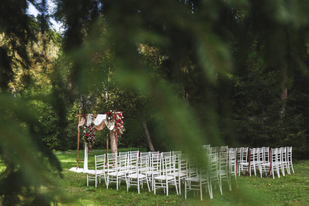 istock Wedding ceremony in rustic style decorated with different red flowers, white textile and chairs in forest 1010487914