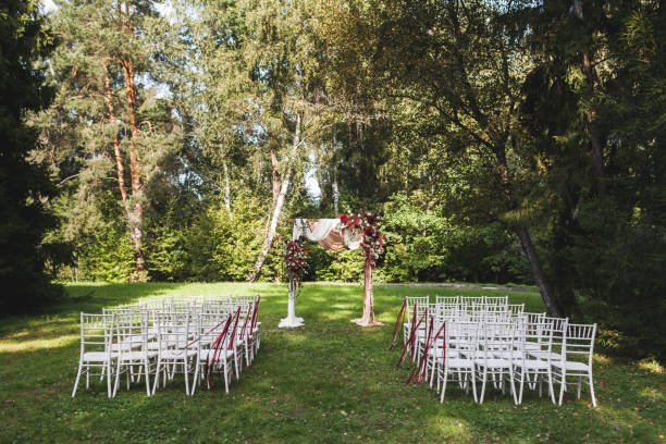 istock Wedding ceremony in rustic style decorated with different red flowers, white textile and chairs in forest 1010487926