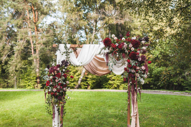 istock Wedding ceremony in rustic style decorated with different red flowers, white textile and chairs in forest 1010487946