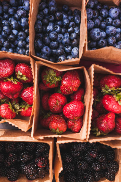 istock Set of different fresh berries in small craft paper boxes on wedding reception table, rustic style, summer mood 1010488222
