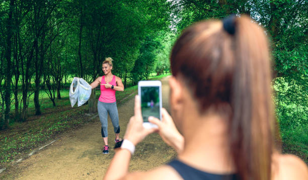 Girl taking picture of a friend after plogging Girl taking a picture of a friend with trash bags after plogging. Selective focus on girl in background moving activity photos stock pictures, royalty-free photos & images
