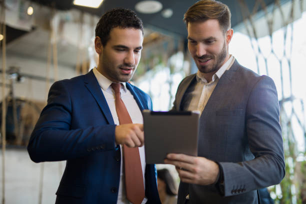 istock Two young businessmen discussing business strategy using digital tablet 1010507684
