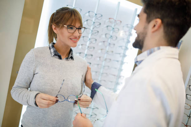 istock Selecting eyeglasses in optical store with assistance of optometrist 1010511014