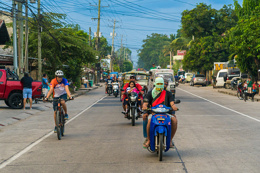 Negros Oriental, Asia - June 19, 2018: Negros Oriental showing cars tricycles multicab bicycles and two wheeled motorcycles with passengers in the province street in the Dumaguete area with people on the background