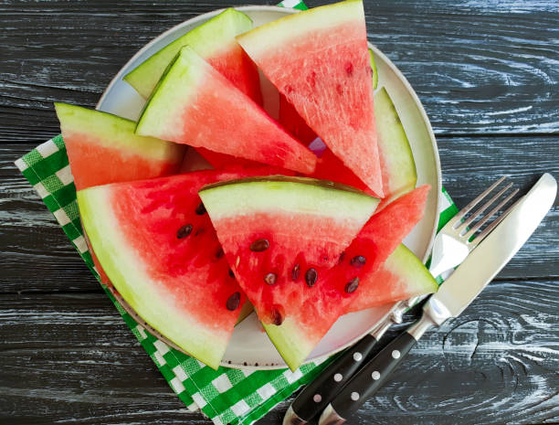 istock ripe watermelon piece, plate on a black wooden background 1010514708
