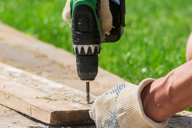 istock electric screwdriver in males hand in textile glove outdoors. Man working with a hand tool on the backyard. 1010517518