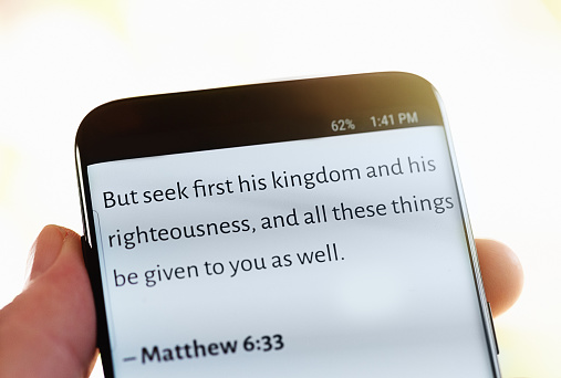 A quotation from the Gospel according to Saint Matthew beginning 'but seek first his kingdom' displayed on the screen of a mobile phone.