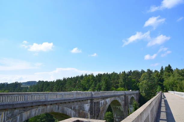 Two large brick and concrete railway bridges seen from the top with trees surrounding them and some white puffy clouds visible on the summer sky seen during one of travels around Poland