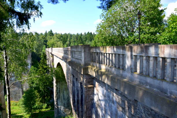 istock Large brick and concrete railway bridge seen from the side with trees surrounding them and some white puffy clouds visible on the summer sky seen during one of travels around Poland 1010530964