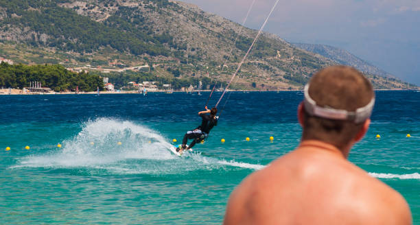海でカイトボーディングをする男性を見ている男性の背面図 - kiteboarding sunlight croatia dalmatia ストックフォトと画像