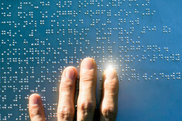 The fingers are touching the metal plate written in the Braille letters; helps the blind to recognize and communicate through the text. stock photo
