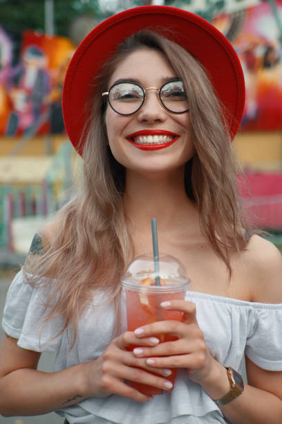 istock Cheerful young woman holding a drink while smiling showing teeth 1010542722