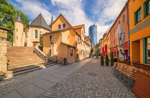 View on the famous, recently renovated restaurant street Wagnergasse and St. Johannes Baptis church in downtown with the landmark 144m tall tower of Jena in tha background on beautiful summer afternoon. \n\nNikon D800, 11mm, F8