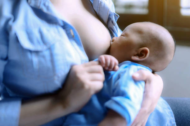 sleeping baby in the hand of mother; Young mom breast feeding her newborn child; Young mom breast feeding her newborn child; Lactation infant and family concept. stock photo