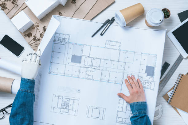 istock partial view of male architect with prosthetic arm working with blueprint at table with rulers, smartphone and digital tablet 1010552854