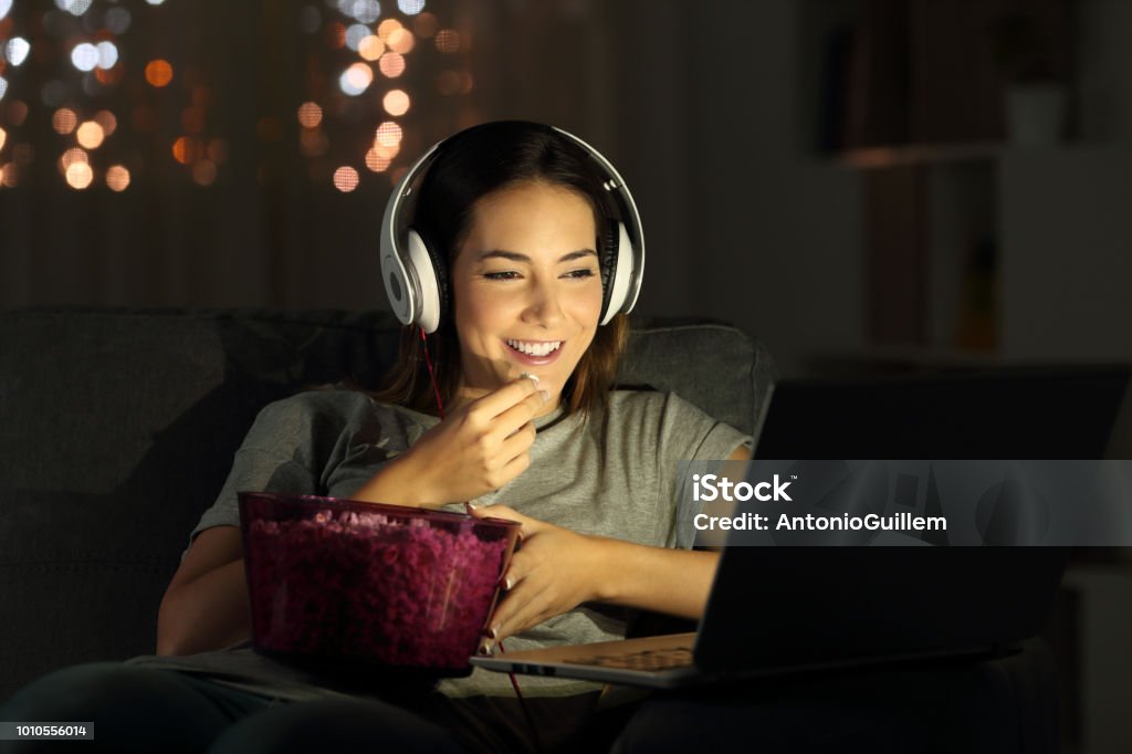 Woman watching online tv in the night Single woman watching online tv in the night sitting on a couch in the living room at home Movie Stock Photo