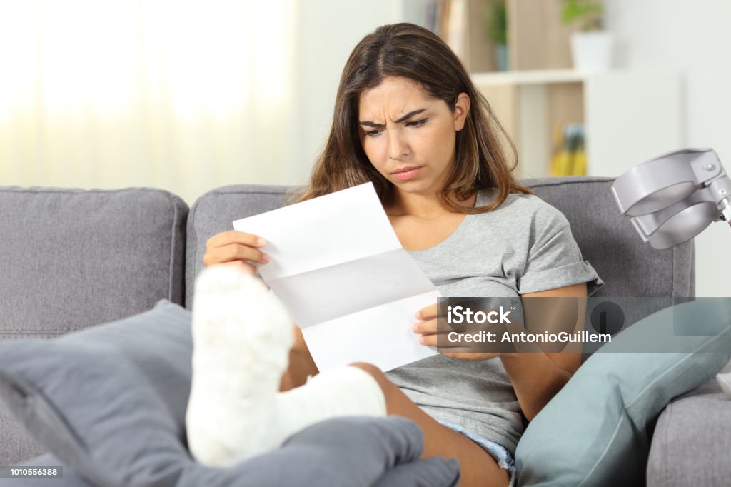 Worried disabled woman reading a letter Worried disabled woman reading a letter sitting on a couch in the living room at home Financial Bill Stock Photo