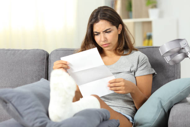 Worried disabled woman reading a letter Worried disabled woman reading a letter sitting on a couch in the living room at home claim form photos stock pictures, royalty-free photos & images